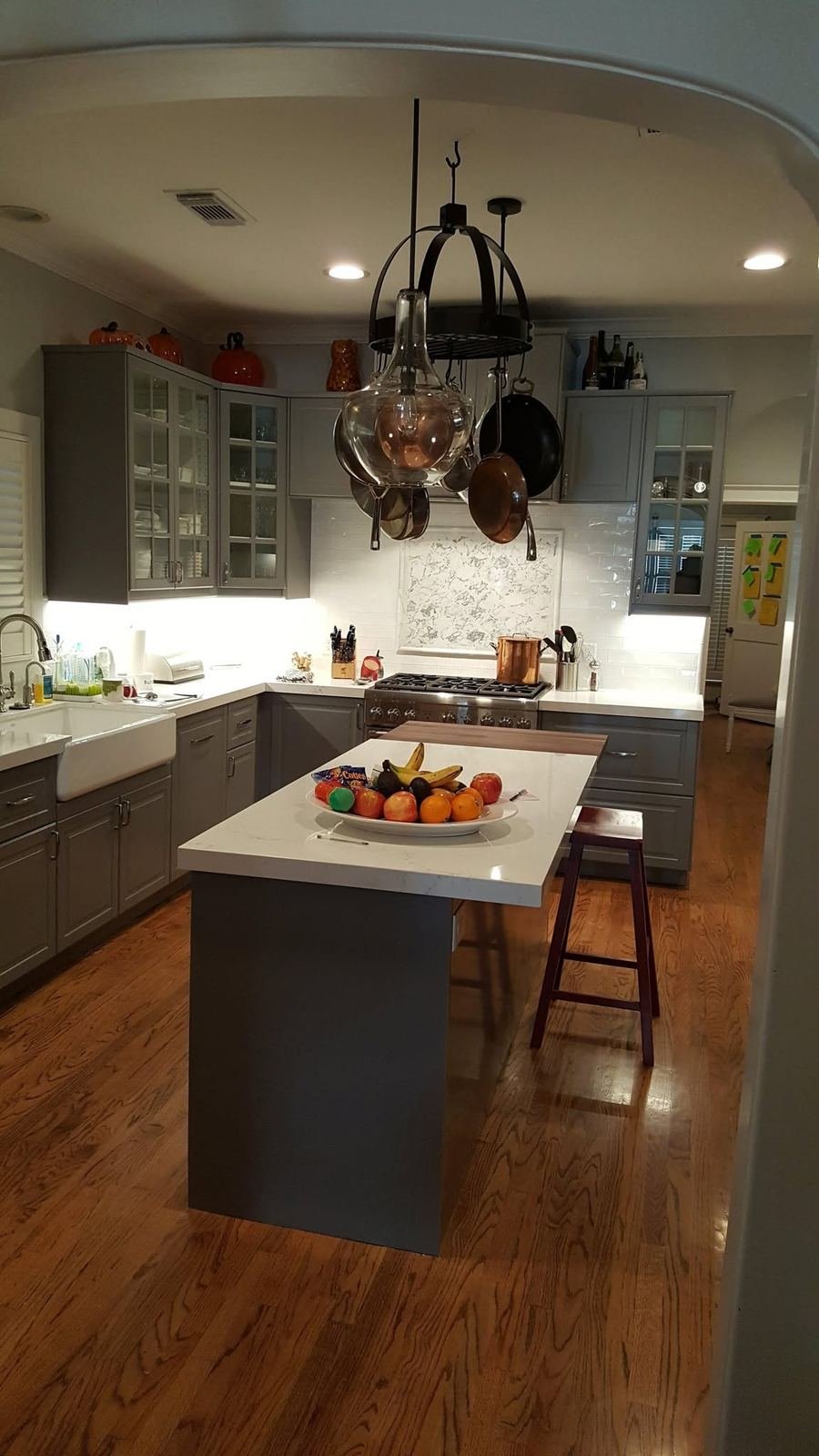 Kitchen island with quartz countertop and pendant pot rack in a renovated kitchen