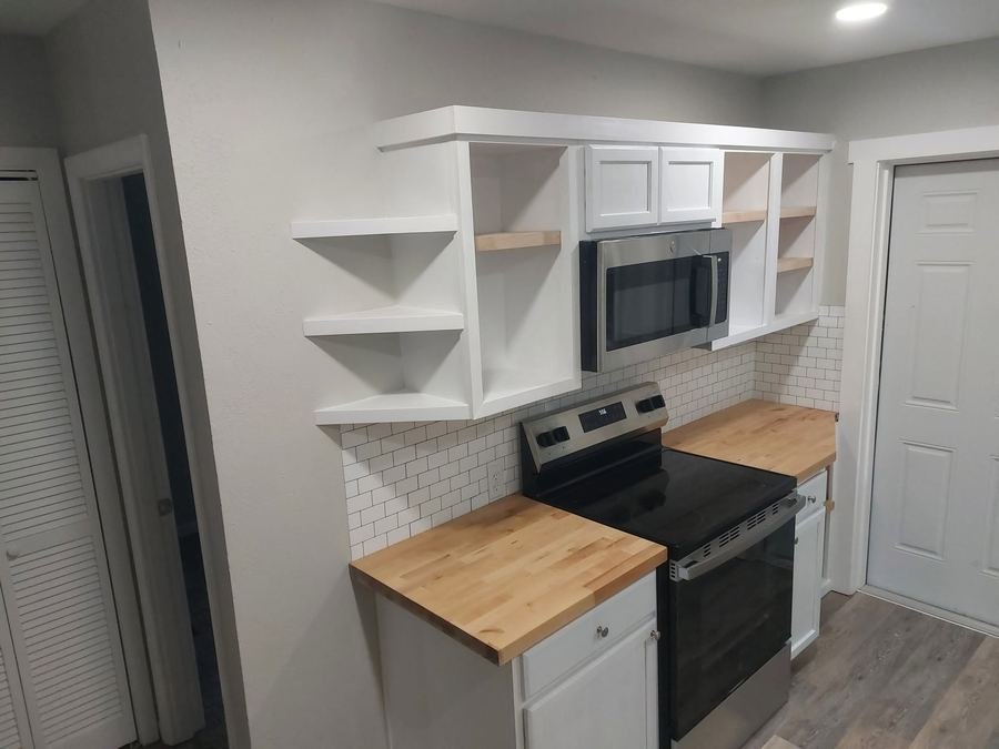 Kitchen cabinetry with custom open corner shelving beside a microwave nook