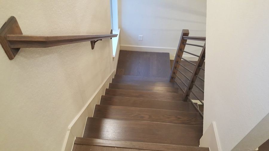 Wide view of a staircase descending toward a landing with rod railing